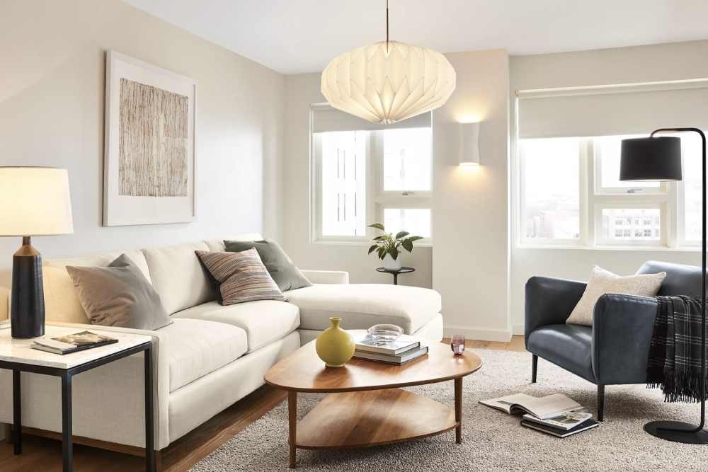 A cream futon facing a blue leather armchair in a well-lit living room with a stunning geometric hanging lamp